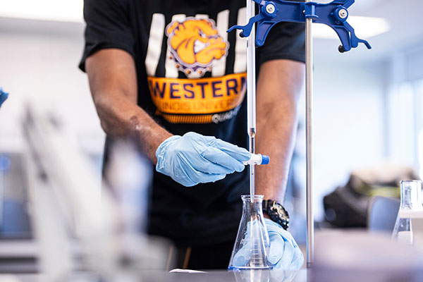 arms of a student using a vial and beaker for testing