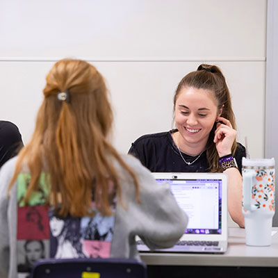 two college students working at laptops