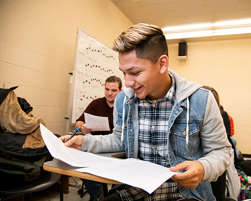 a student in a classroom looking at a couple of sheets of music