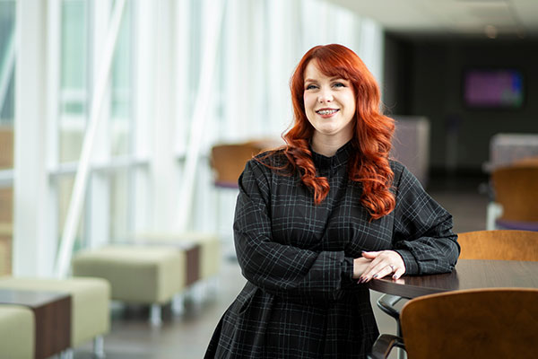 woman sitting at a table in a library looking off into the distance