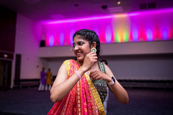 young woman of south asian descent dancing while wearing traditional dress