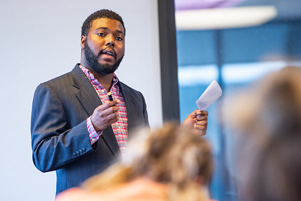 young man in a suit speaking to a group of people