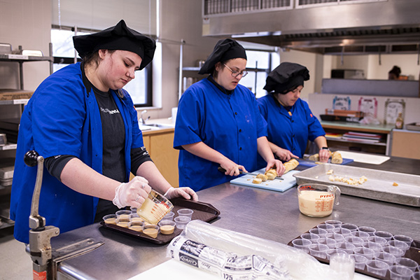 three students working in a kitchen