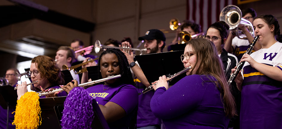 two flutes in the foreground, photo of alumni in the WIU pep band