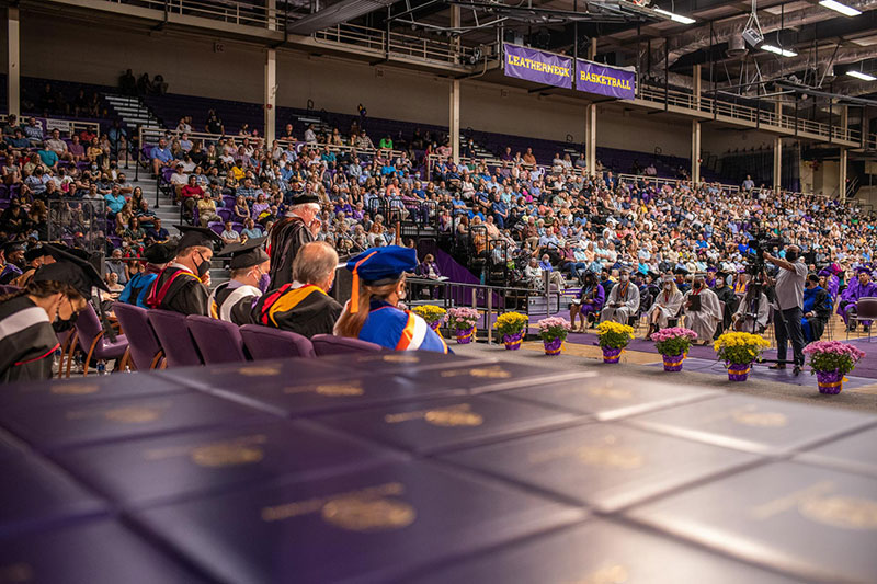 white flowers with purple pots and gold bows at graduation